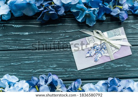 top view of wooden green background with blue floral borders and envelope
