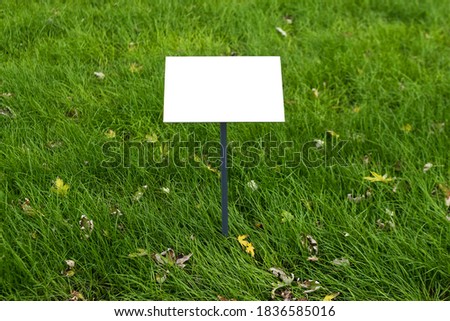 Empty sign board on grass with space for caption. Property house for sale sign board. Notice board with copyspace for prohibition.