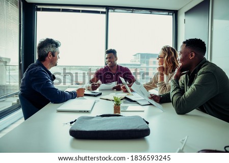 Caucasian male boss briefing team on goals for start up of new business sitting around table in conference room