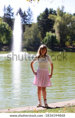Middle of autumn. smiling stylish 30 year old woman in white dress in the autumn park enjoying autumn and catching falling yellow leaves. Sunny warm day, golden fall