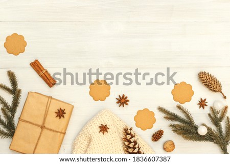 Christmas background with fir branches,gift in craft paper ,cookies and a cone. On light boards, top view with space