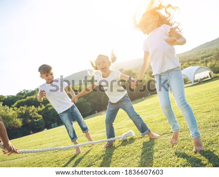 Children play tug of war in the park. A group of cute children playing actively together in nature. Cute kids outdoors. High quality photo.
