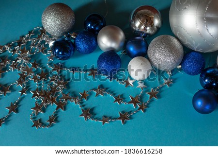 Christmas decorations. Christmas balls of blue, white and silver colors of different sizes on a turquoise background.