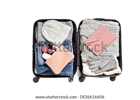 Flat lay with open suitcase with casual clothes for autumn, winter vacations over white background. Winter holidays, travel, tourism, flight luggage concept. Top view