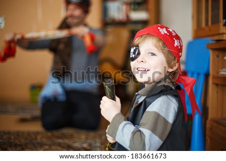 Little preschool boy of 4 years celebrating birthday in pirate costume, indoors with father on background