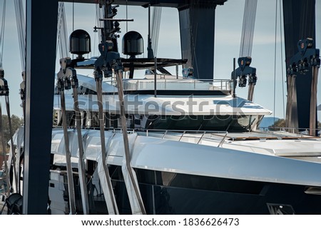 Super Yacht hauled out in shipyard, being lifted by industrial crane for refit or maintenance yard period  Royalty-Free Stock Photo #1836626473