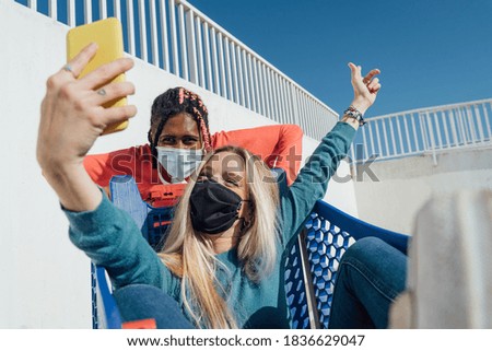 Portrait of two protected girls wearing masks, laughing and taking happy pictures. Concept of happiness and security.