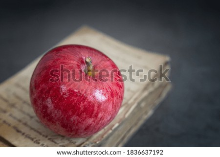 Still life: a ripe red Apple on an old book on a dark background. Side view, copy space