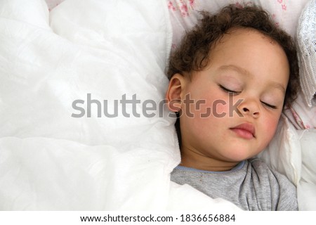 boy sleeping wrapped up in blanket after having a good sleep in bed stock photo