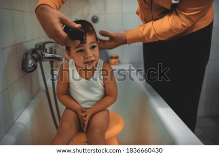 Father cutting son's hair at home during the 2020 pandemic lockdown. Covid-19 social distancing