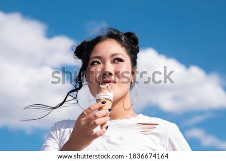 asian woman eating ice cream blue sky