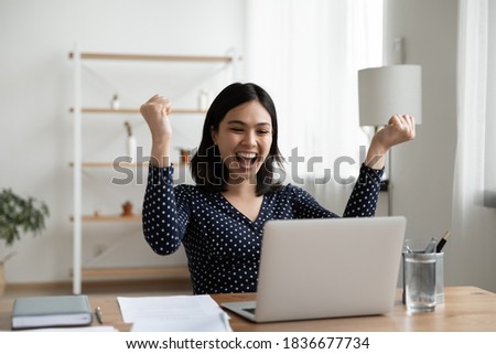 Excited young Vietnamese woman sit at desk at home office triumph reading good unexpected news or email on laptop. Overjoyed asian female look at screen feel euphoric win lottery online. Royalty-Free Stock Photo #1836677734