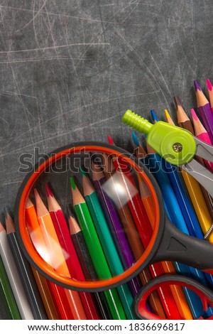 multicolored school supplies lie on black chalkboard, short focus, partial blur