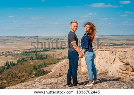 A romantic couple a man and a woman stand on the edge of a cliff on a White rock in the Crimea with a view of the rural landscape