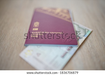 Picture of a Swedish Passport that reads: European Union Sweden Passport, and has a blurry Two Thousand Colombian Pesos Bill Partially Inside