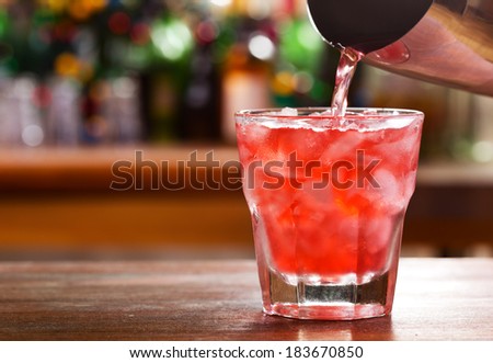 pouring cocktail into a glass
