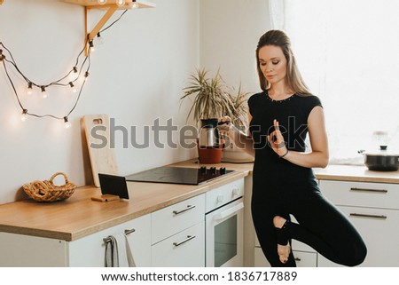 Yogi woman stretches in the kitchen at home. Morning work-out. Sports at home
