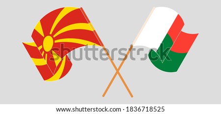 Crossed and waving flags of Madagascar and North Macedonia