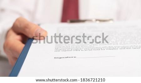 Businessman reaching out documents to camera and offering to sign them.