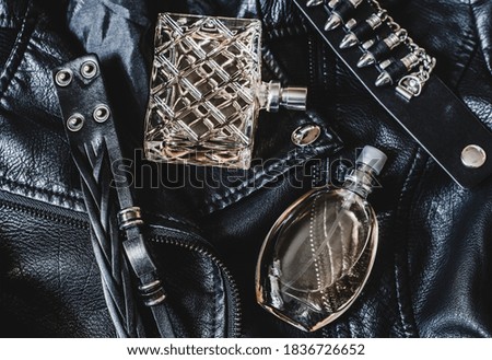 Two bottles of perfume for women on a black leather jacket. Women's perfume and leather bracelets