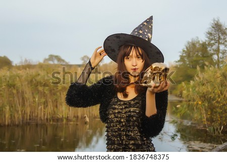 Halloween a young beautiful witch conjures a ritual skull preparing for the Sabbath