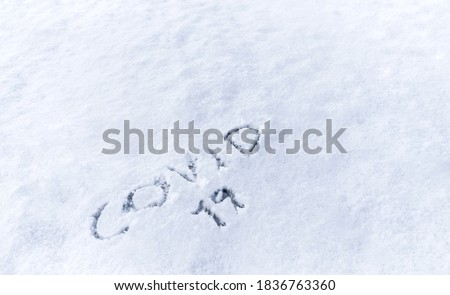 Covid 19 text written in the snow. Concept of covid-19 pandemic usable for background or poster for the 2020 winter and christmas campaign.