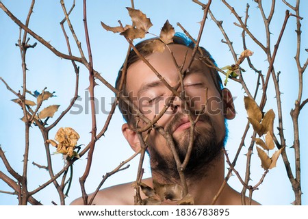 portrait of a guy in dry branches of a rose