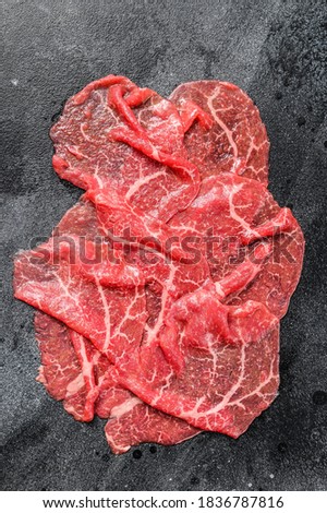 Slices of Beef Capriccio, raw meat. Black background. Top view