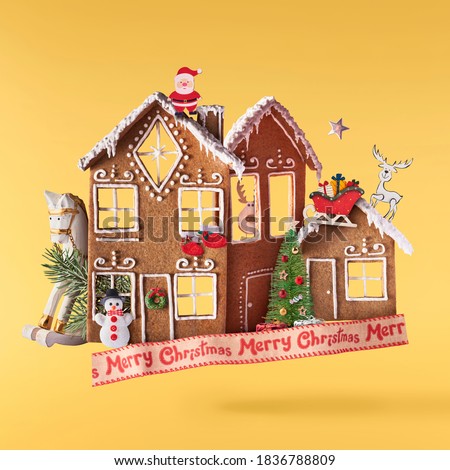 Christmas holliday card. Flying in the air gingerbread houses with christmas decorations isolated on the yellow background. Merry christmas levitation concept. High resolution image.