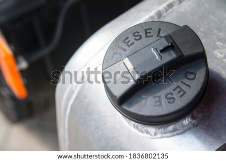 Black plastic cap of aluminum gas tank in silver color with the inscription "DIESEL". The fuel tank of the truck is closed with a cap. The concept of rising fuel prices in the world. Royalty-Free Stock Photo #1836802135