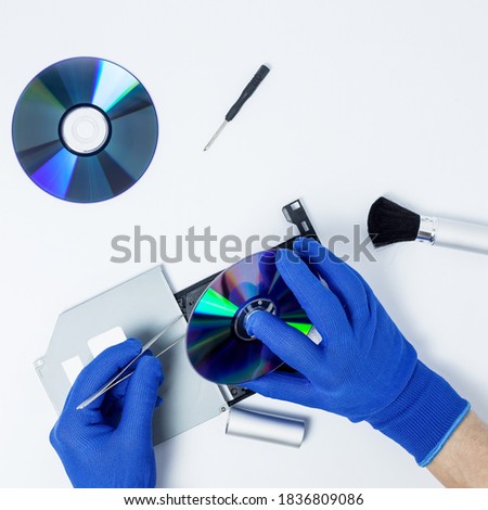 Hands of the person performing maintenance and repair DVD ROM. CD disks with tools. Isolated background. Top view.
