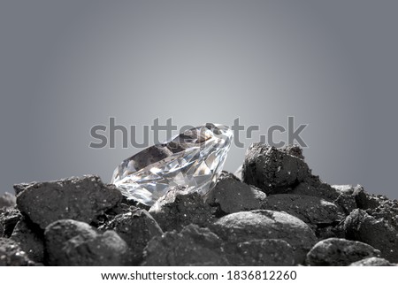 A diamond in a pile of coal shows the evolution of a precious gem. Royalty-Free Stock Photo #1836812260