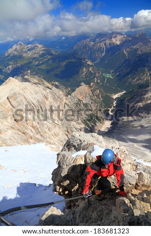 Sunny day and a tourist ascending the via ferrata route, Dolomite Alps, Italy
