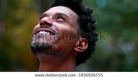 Positive african american man feeling hope and faith looking up