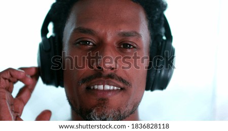 Portrait black man putting on headphones listening to podcast, music, audiobook