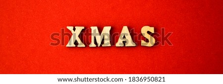 Text XMAS made of wooden letters on red background. Banner size. New year and Merry Christmas greeting card