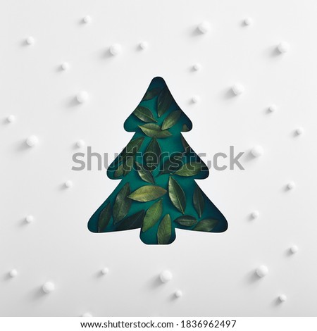 Christmas minimal concept - xmas tree silhouette made with green leaf and snowfall pattern. Square composition, flat lay, view from above. Merry christmas background. New year christmas.