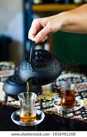Black tea and teapot in hand, Turkish tea glasses and old iron teapot