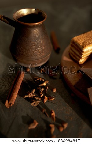 Tasty desserts, cake, coffee and cinnamon on the dark background