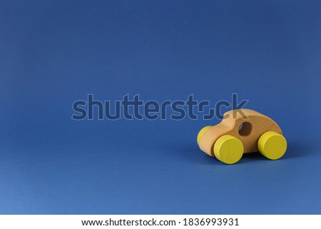 Wooden toy car with yellow wheels Concept of environmentally friendly toys for children on a blue background horizontal photo side view.