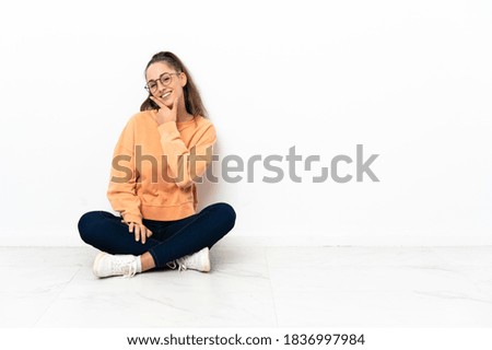 Young woman sitting on the floor happy and smiling
