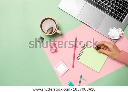 Woman working with modern laptop, took a break to drink a cup of tea with candy