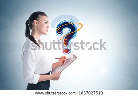 Portrait of serious young businesswoman with clipboard standing near gray wall with question mark drawn on it. Mock up