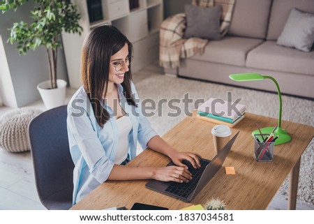 Photo of charming young lady sit chair typing keyboard shiny smile wear spectacles shirt in home office indoors