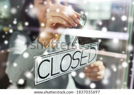 small business, people and service concept - young woman hanging banner with closed word on door or window in winter over snow