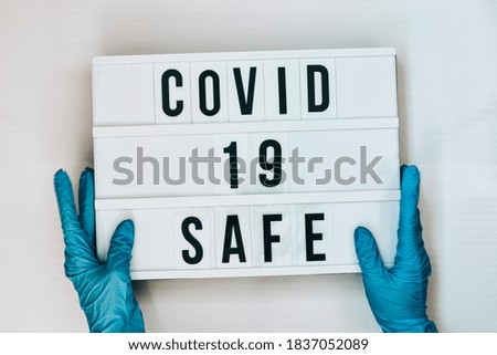 Doctor in protective gloves holding Lightbox with text COVID 19 SAFE. Back to school. Social distancing. School quarantine concept.