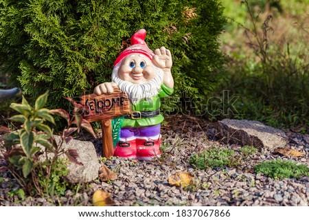 
Figurine of a garden gnome in the garden with a sign.
