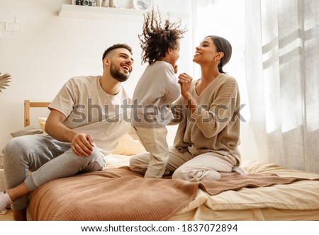 happy family multiethnic mother, father and son  laughing, playing,and jumping in bed in bedroom at home Royalty-Free Stock Photo #1837072894