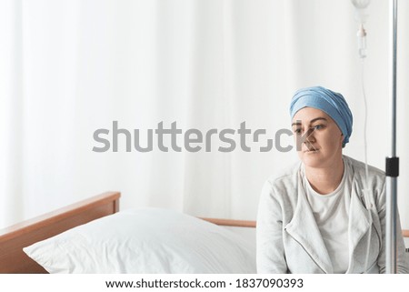 Young woman in scarf suffering from cancer taking a drip