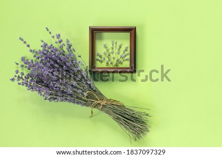 Wooden frames with  beautiful bouquet of fragrant lavender in  rustic style for gift on green wall. Holiday party decoration. Vintage floral card. Interior concept.